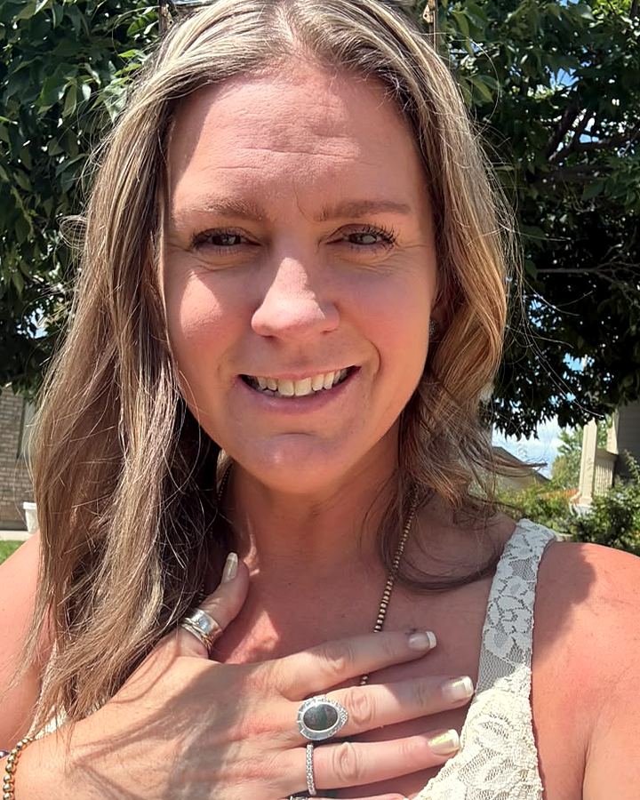 Amy Beth, founder of Revival Jewelry Co., smiling outdoors and showing a silver ring
