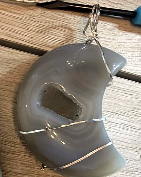 A wire-wrapped agate moon pendant with a small crystal center