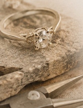 A restored engagement ring resting on a piece of raw stone at the workbench